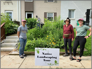 Three people in front of garden with Native Landscaping Tour Sign